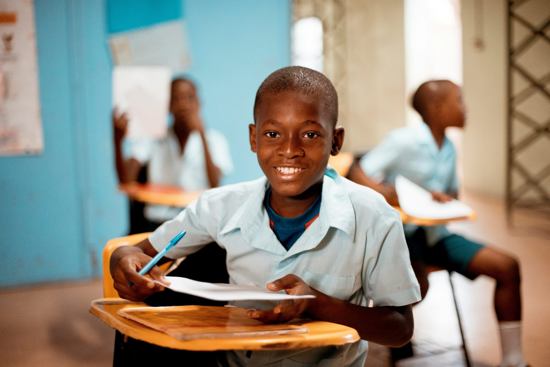 Smiling boy in classroom with paper